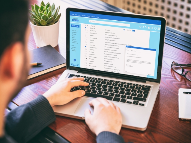 Email message communication. Man working with a computer, client mail list on laptop screen, office desk background.